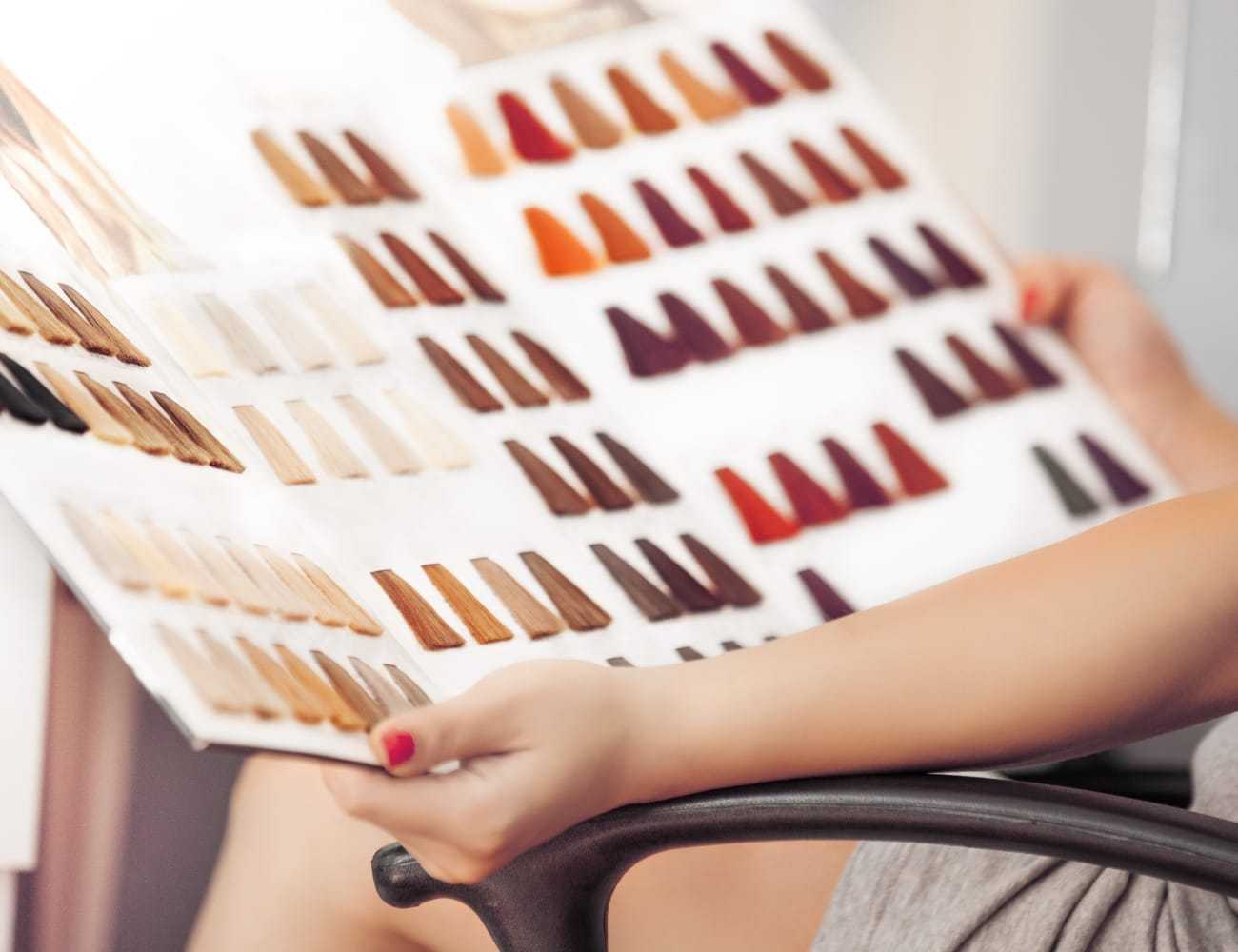 Hair color swatches in hand for selecting various shades at a salon.
